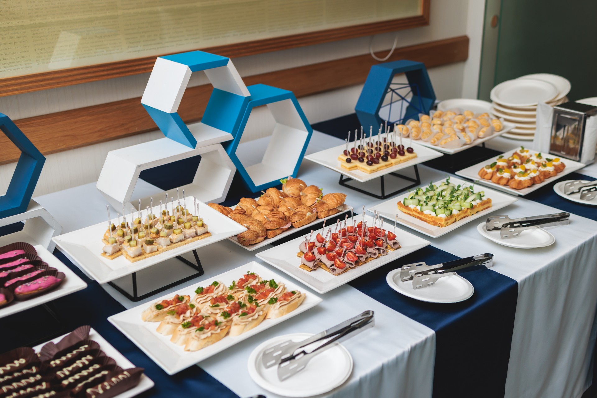 Beautifully decorated banquet catering table, with variety of with different food snacks appetizers on corporate birthday party event or wedding celebration, canape, salad, delicatessen setting